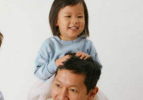 a smiling dad with a toddler sitting on his shoulder