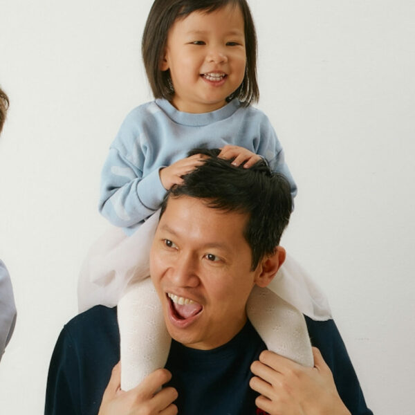 a smiling dad with a toddler sitting on his shoulder