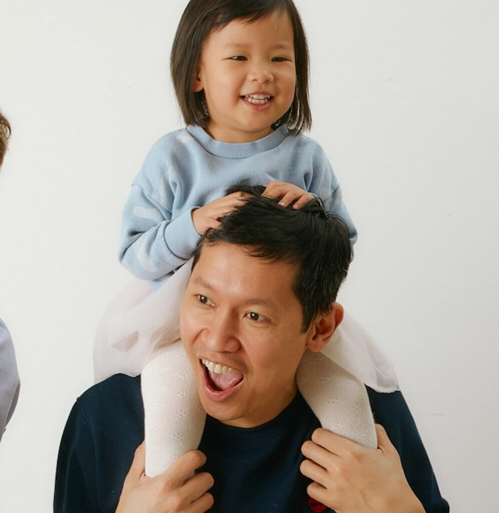 a smiling dad with a toddler sitting on his shoulder