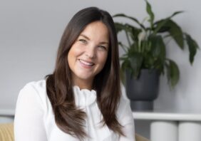 Jen Harris in a white blouse sitting on a sofa