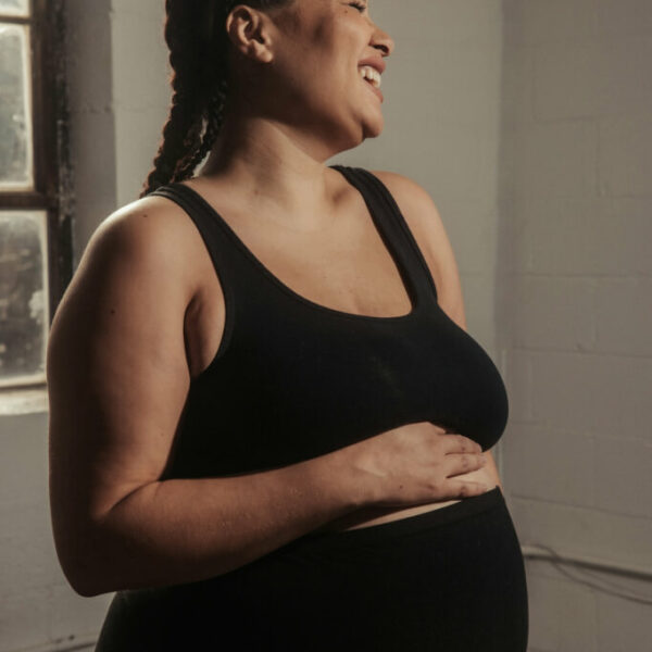 A pregnant woman in black activewear holding her pregnant belly