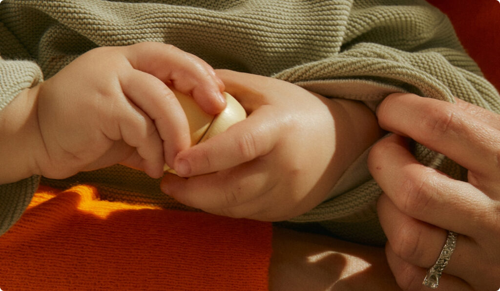 Close up of a baby hand holding a wooden toy