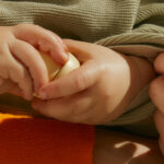 Close up of a baby hand holding a wooden toy