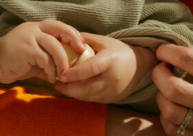 Close up of a baby hand holding a wooden toy