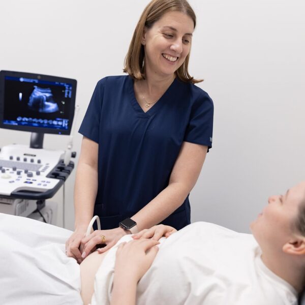 A clinician sitting down performing ultrasound scan to a client