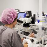 Lab technician using a lab equipment while sitting down
