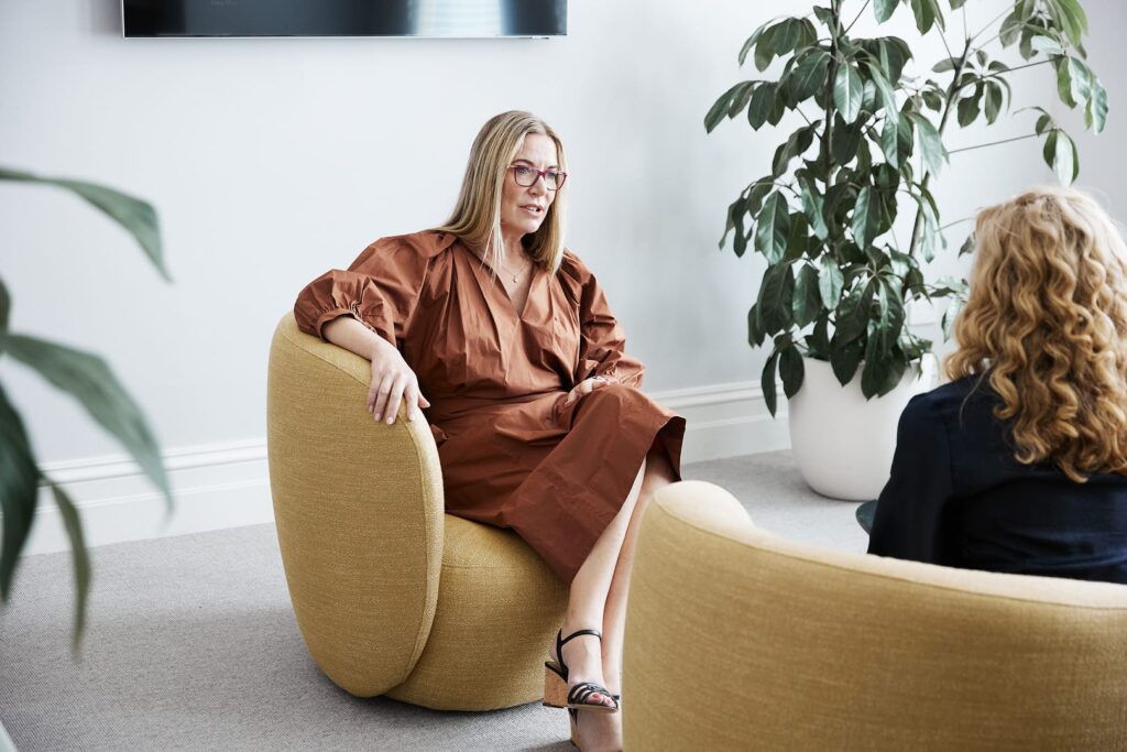 Dr Rachael Knight sitting down on a sofa speaking to a colleague